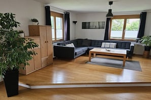 Ein modernes Wohnzimmer mit einem Ecksofa, einem Couchtisch und einer Holzkommode.