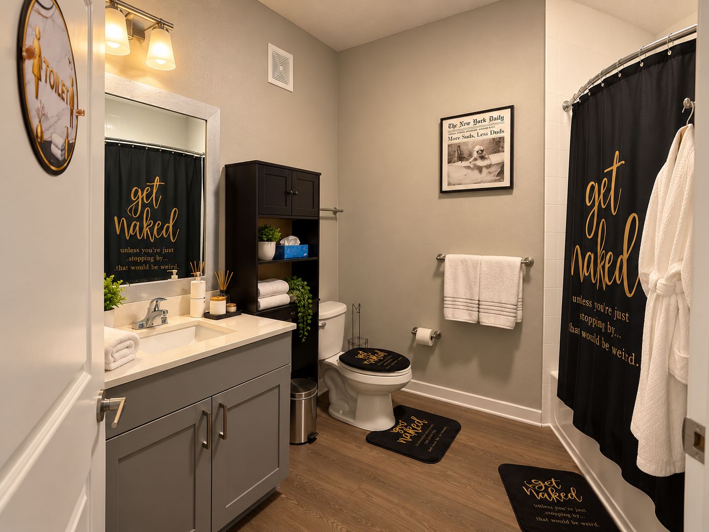 Une salle de bain moderne avec des toilettes, un lavabo et un meuble-lavabo. On y trouve des serviettes et un magazine accroché au mur.