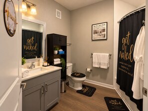 A modern bathroom with a toilet, sink, and vanity. There are towels and a magazine on the wall.
