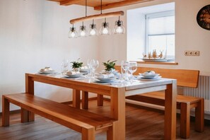 Een houten eettafel gedekt met borden, glazen en een potplant.