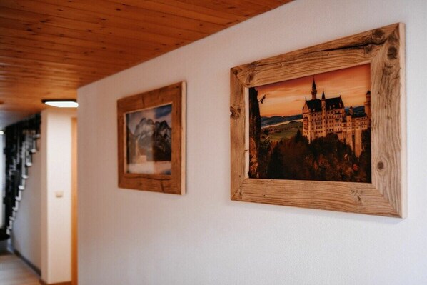 Ein Korridor mit Holzboden und zwei gerahmten Bildern an der Wand.