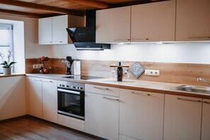 Een moderne keuken met witte kasten, een zwarte afzuigkap en een houten aanrecht.