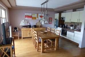 A modern kitchen with wooden cabinets, a dining table, and a coffee machine. - on the dike in Grimmershörn Bay (Cuxhaven)
