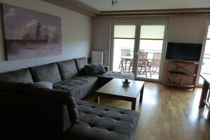 A living room with a sofa, a coffee table, and a television on a stand. - on the dike in Grimmershörn Bay (Cuxhaven)