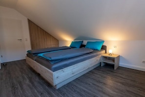 A bedroom with a wooden bed, a nightstand, and a wall-mounted cabinet. - Holiday home with 3 bedrooms (Braunlage)