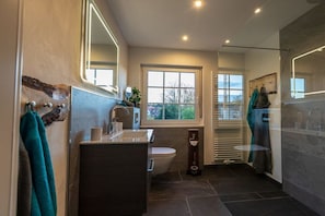 Een moderne badkamer met een wastafel, toilet en douchehoek.
