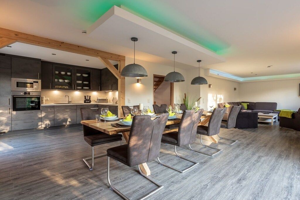 Une cuisine moderne dotée d’appareils électroménagers intégrés et d’un coin repas avec une table et des chaises en bois.