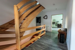 A wooden staircase leading to an upper floor, a white wall with a heart-shaped decoration, and a doorway to a room with a radiator. - Holiday home with 3 bedrooms (Braunlage)