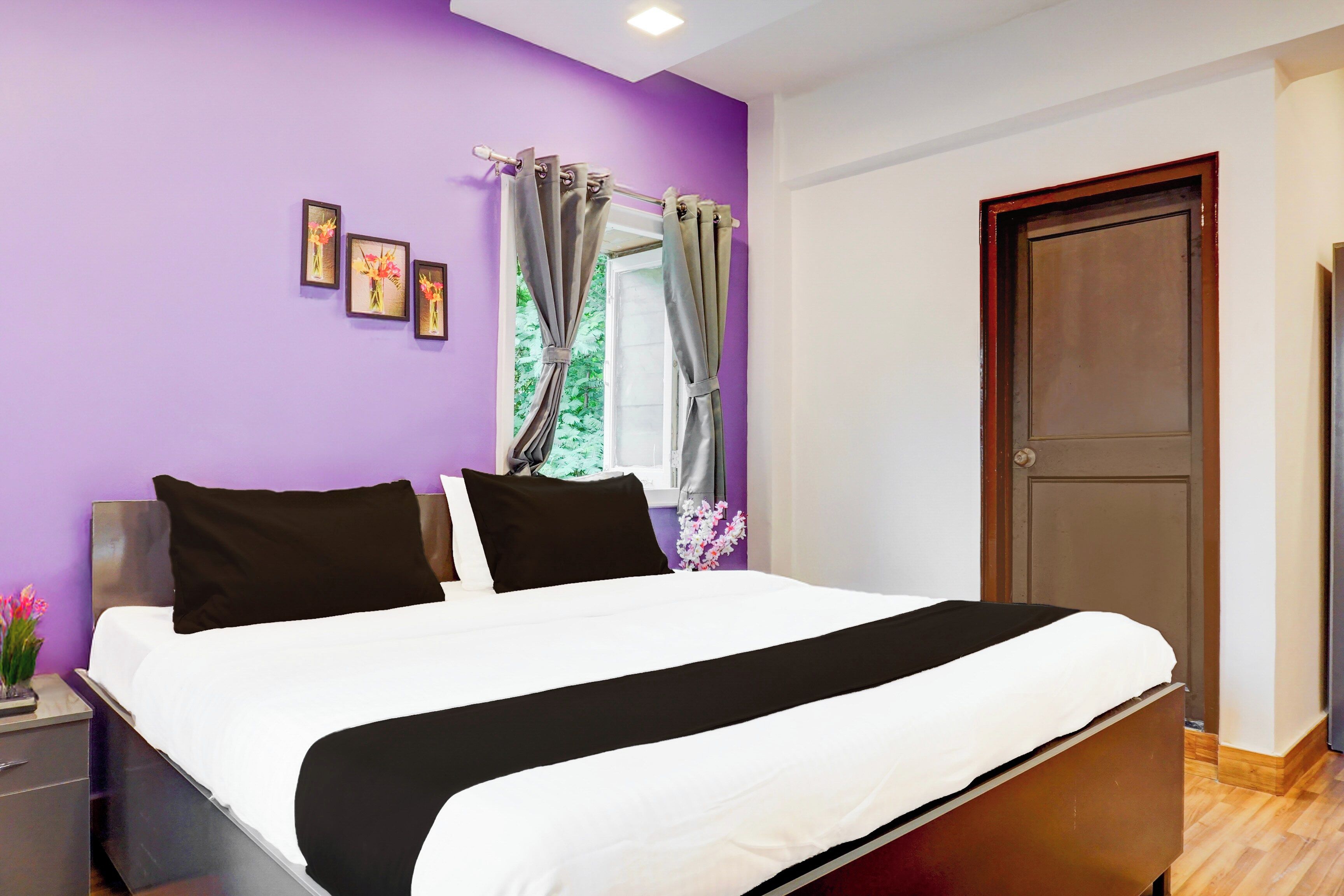 A bedroom with a bed, a nightstand, a dresser, a door, and a window with curtains.