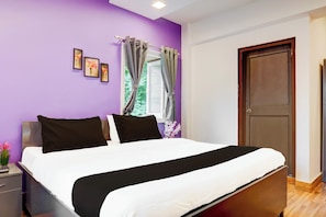 Un dormitorio con cama, mesita de noche, cómoda, puerta y ventana con cortinas.