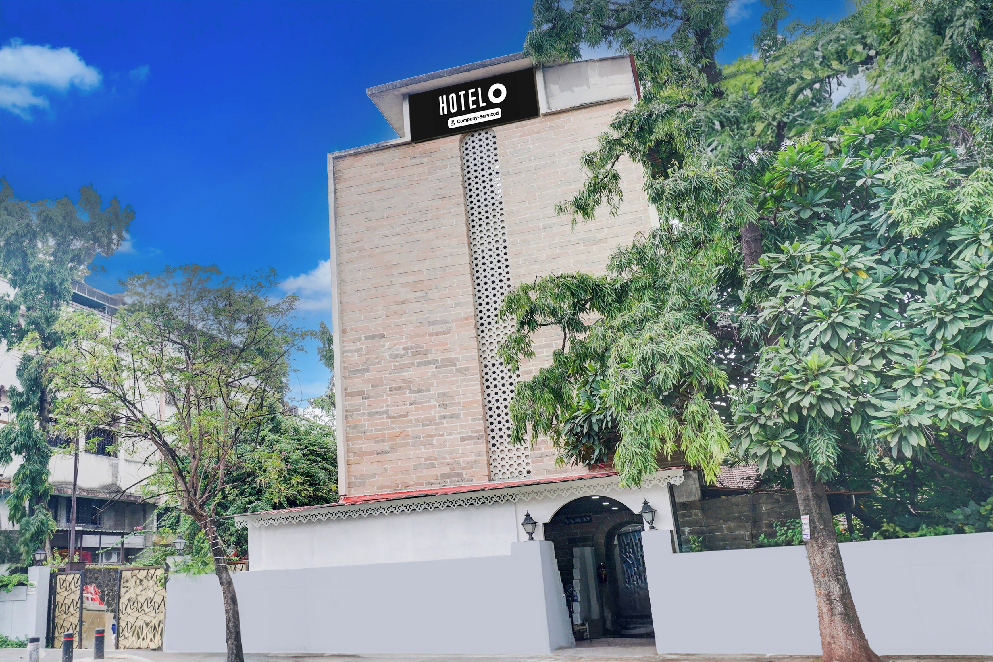 Un hotel con un cartel llamativo, fachada de ladrillo y entrada protegida por una reja.