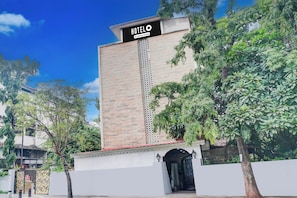 Un hotel con un cartel llamativo, fachada de ladrillo y entrada protegida por una reja.