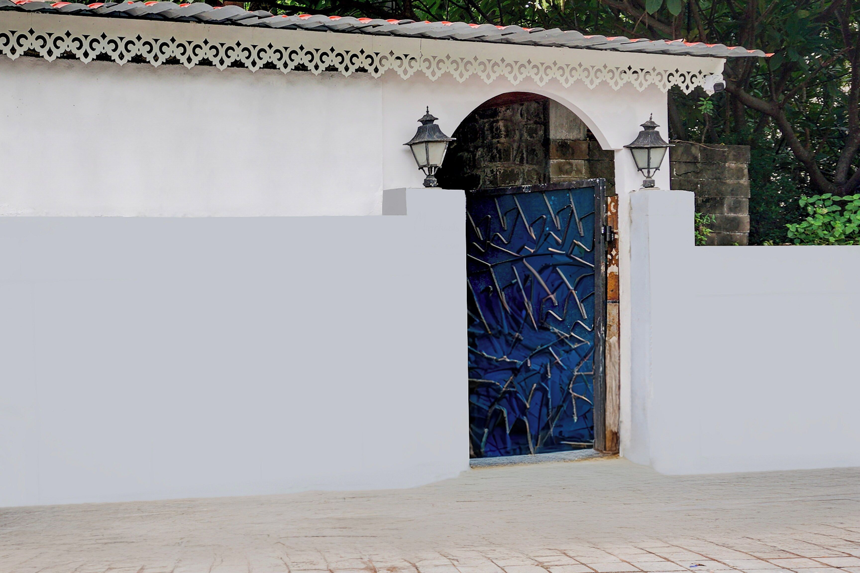 A white building with a blue door and two wall-mounted lamps.