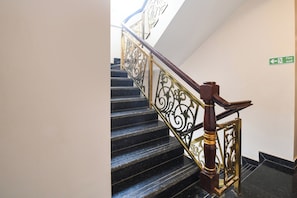 Una escalera con barandillas de metal decoradas y una barandilla de madera, que conduce a un piso superior.