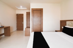 Quarto de hotel com cama, mesas de cabeceira, guarda-roupa e espelho.