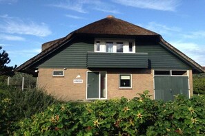 A two-story building with a dark green exterior, a thatched roof, and a sign indicating 'Vrede.' - Holiday home in Buren with swimming pool (Buren)
