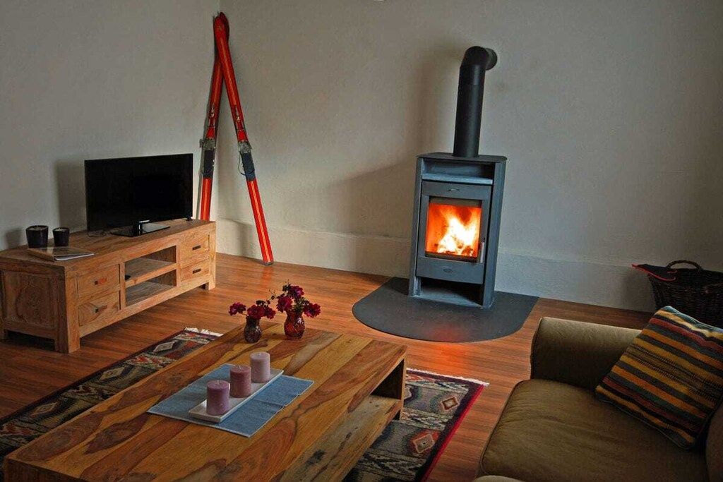 Una sala de estar acogedora con una estufa de leña, un televisor y un sofá cómodo.