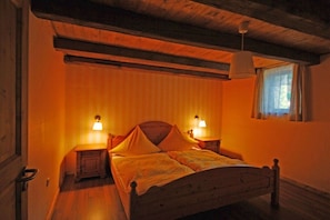 A bedroom with a wooden bed, two bedside lamps, and a window with curtains. - Holiday apartment in Wertach with Wi-Fi (Wertach)