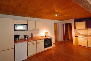 A compact kitchen with wooden flooring, a built-in oven, a microwave, and a coffee maker. - Holiday apartment in Wertach with Wi-Fi (Wertach)
