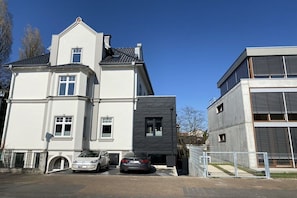 A two-story building with a garage, two cars parked in front, and a modern design. - Holiday apartment with 2 bedrooms (Detmold)