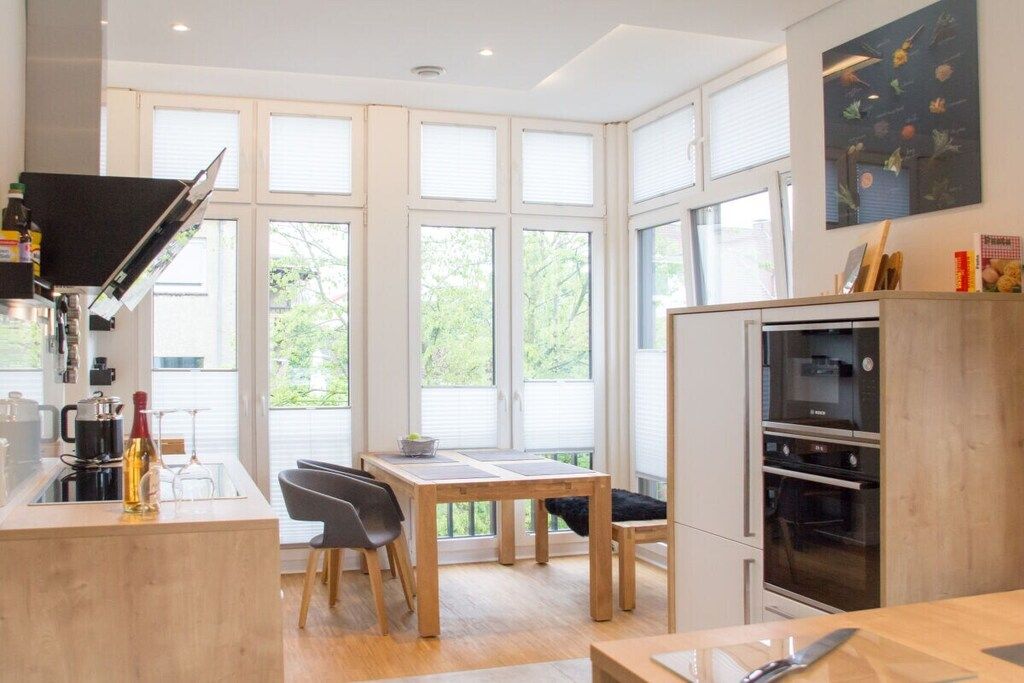 Eine moderne Küche mit Essbereich, großen Fenstern und einem eingebauten Backofen.