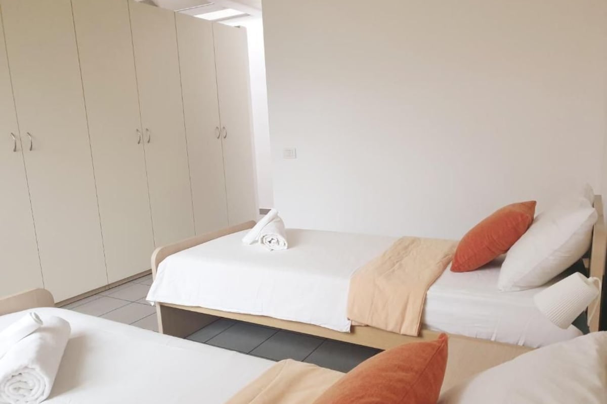 A hotel room with two beds, a wardrobe, and a bathroom.