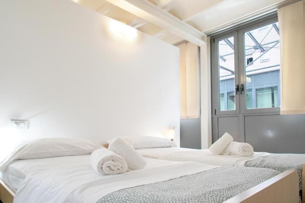 A hotel room with a bed, a window with a view, and a door.
