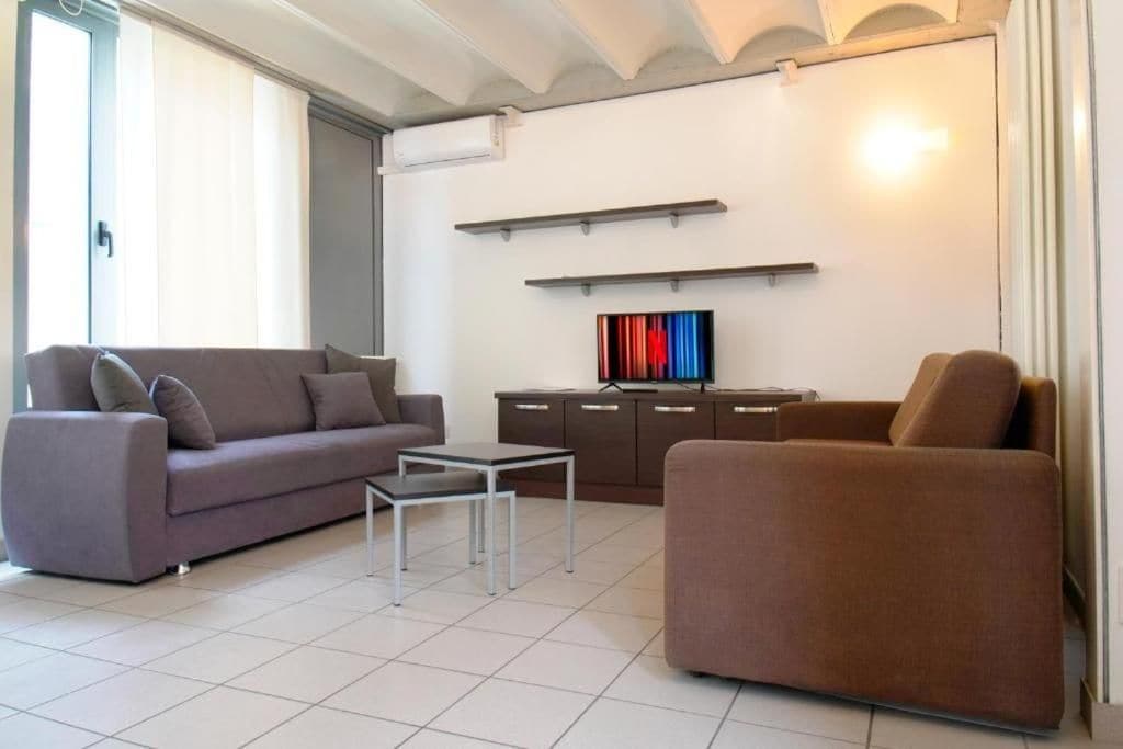 Una sala de estar moderna con sofá, sillón, mesa de centro y mueble para la televisión.