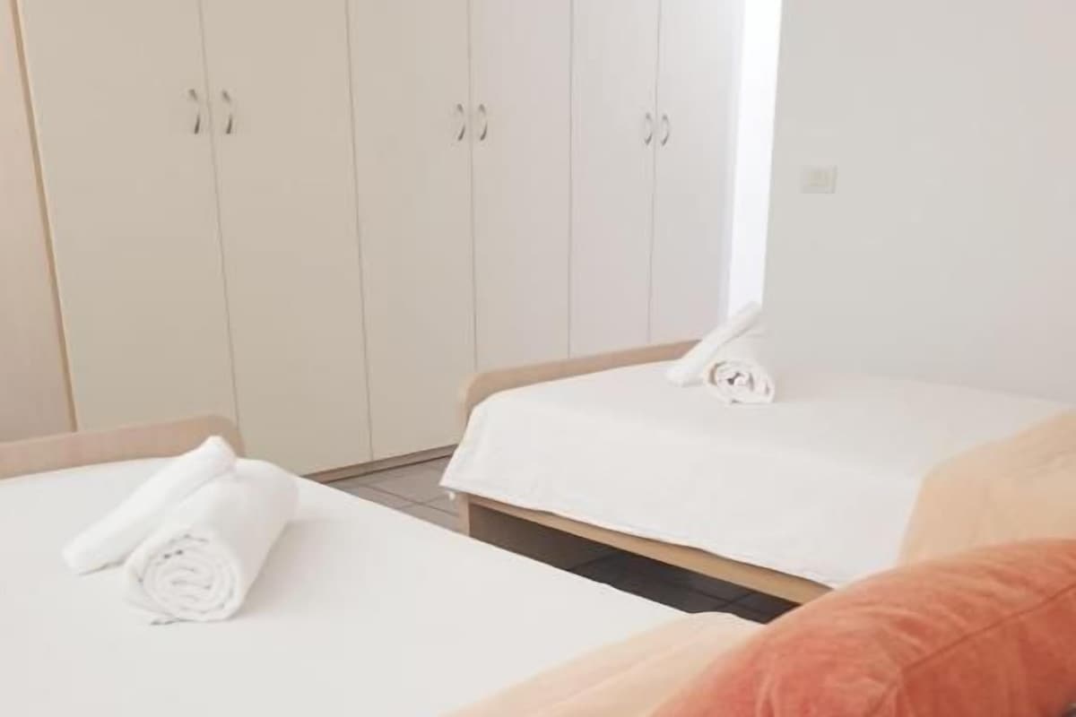 A hotel room with two beds, a wardrobe, and a window.