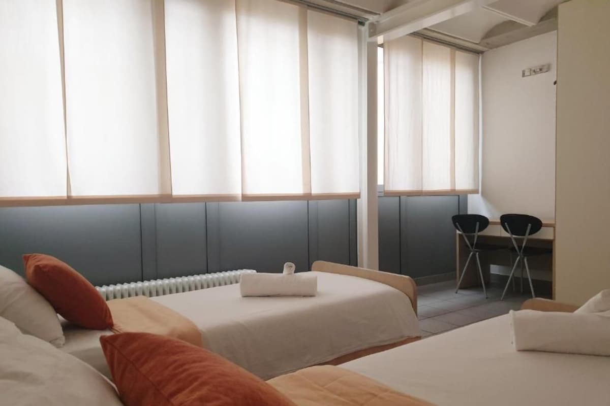 A hotel room with two beds, a desk, and a chair.
