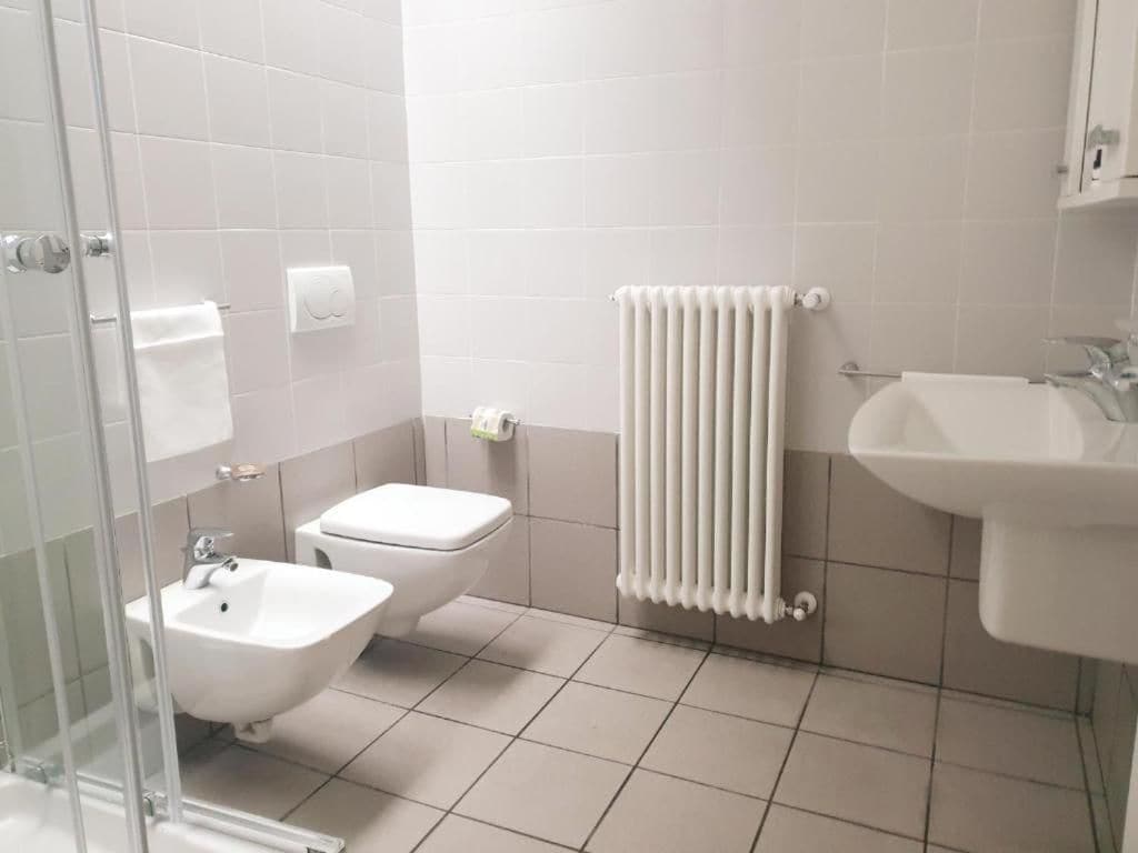 Un baño con bidé, inodoro, lavabo y cabina de ducha de vidrio.