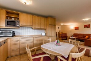 A compact kitchen with wooden cabinets, a microwave, and a dining area with a table and chairs.