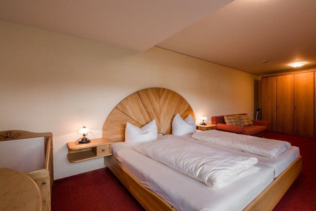 Ein Schlafzimmer mit einem großen Bett, zwei Nachttischen, einem Holzkopfteil, einem roten Teppich und einem Kleiderschrank.
