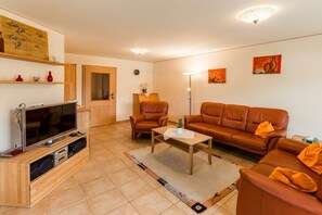 A living room with a sofa, chairs, a coffee table, a TV, and artwork on the walls.