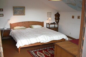 A bedroom with a wooden bed, a nightstand, a lamp, and a red carpet. - Holiday apartment with 1 bedroom (Oy-Mittelberg)