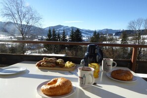 A table with breakfast items and a mug, overlooking a mountainous landscape. - Holiday apartment with 1 bedroom (Oy-Mittelberg)