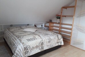 Een slaapkamer met een bed, een houten trap en een klein plankje met bloemen.