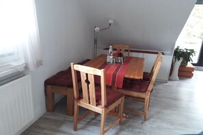 Een eetruimte met een houten tafel en stoelen, een rode tafelkleed en een potplant.
