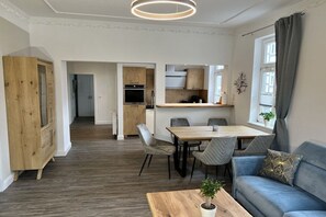 A modern living room with a dining area, kitchen, and a large wooden cabinet. - Holiday apartment with 2 bedrooms (Wernigerode)