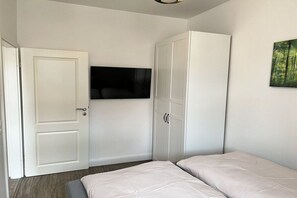 A bedroom with a bed, a wardrobe, and a television mounted on the wall. - Holiday apartment with 2 bedrooms (Wernigerode)