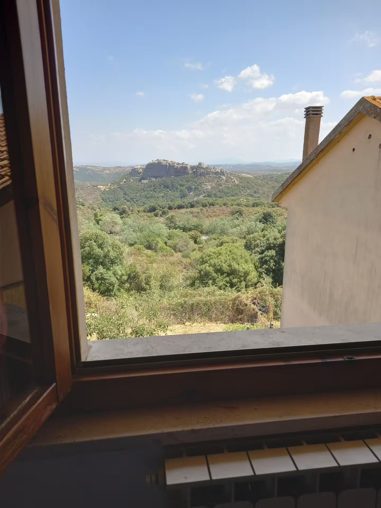 A view through a window with a view of a mountainous landscape and a building in the foreground.