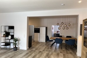 A modern kitchen with a dining area, a built-in bookshelf, and hanging pendant lights. - Holiday apartment with 3 bedrooms (Wernigerode)