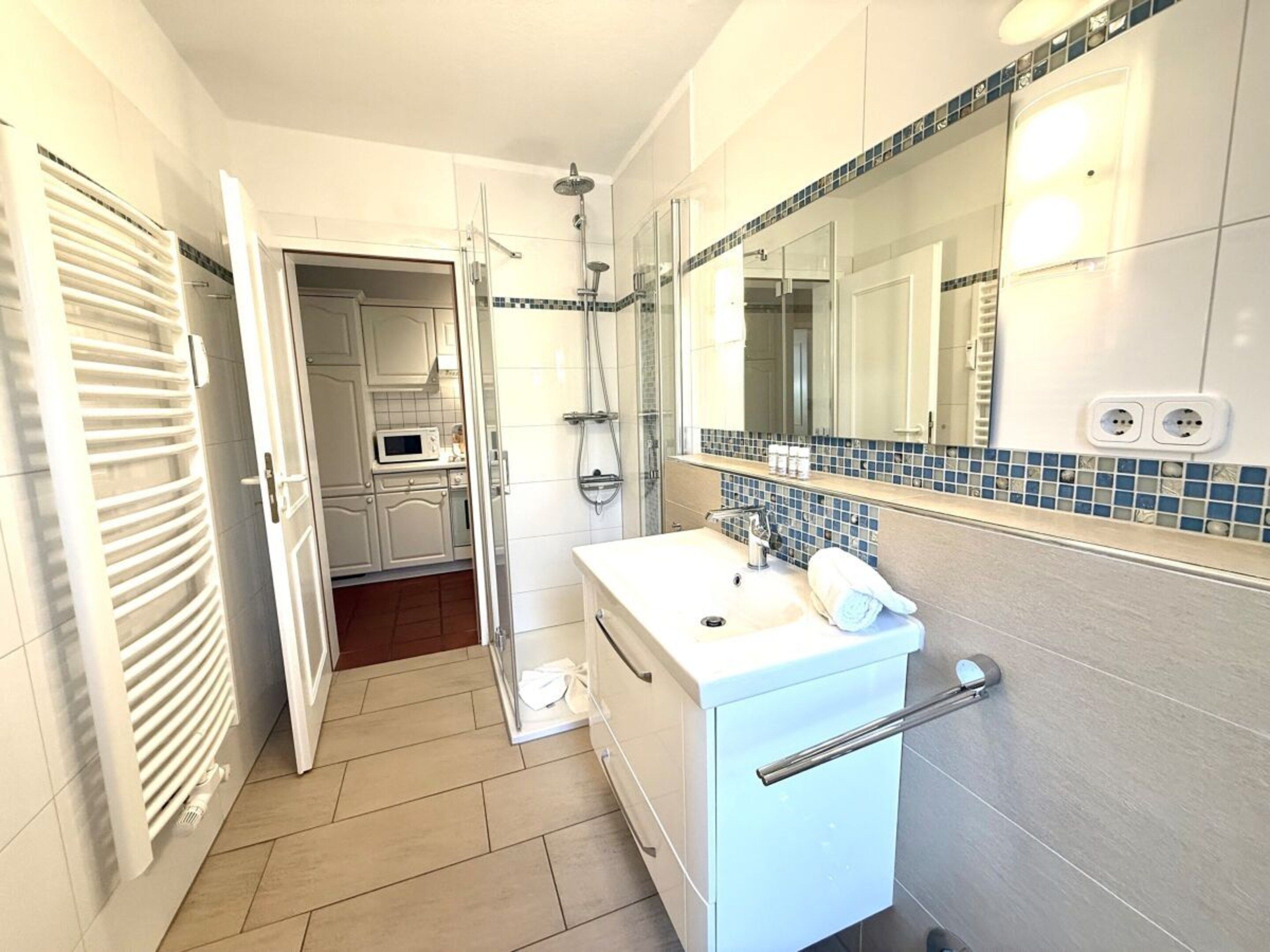 A bathroom with a white sink, a mirror, and a shower.