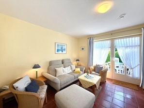 Ein Wohnzimmer mit einer Couch, Sesseln, einem Couchtisch und einem Essbereich mit Tisch und Stühlen.