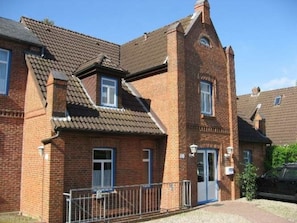 A two-story brick house with a pitched roof, a visible chimney, and a small attached garage. - Holiday Apartment With 1 Bedroom (Wyk auf Foehr)