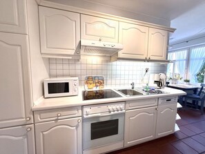Eine Küche mit weißen Schränken, einer Mikrowelle, einem Backofen und einem Spülbecken.