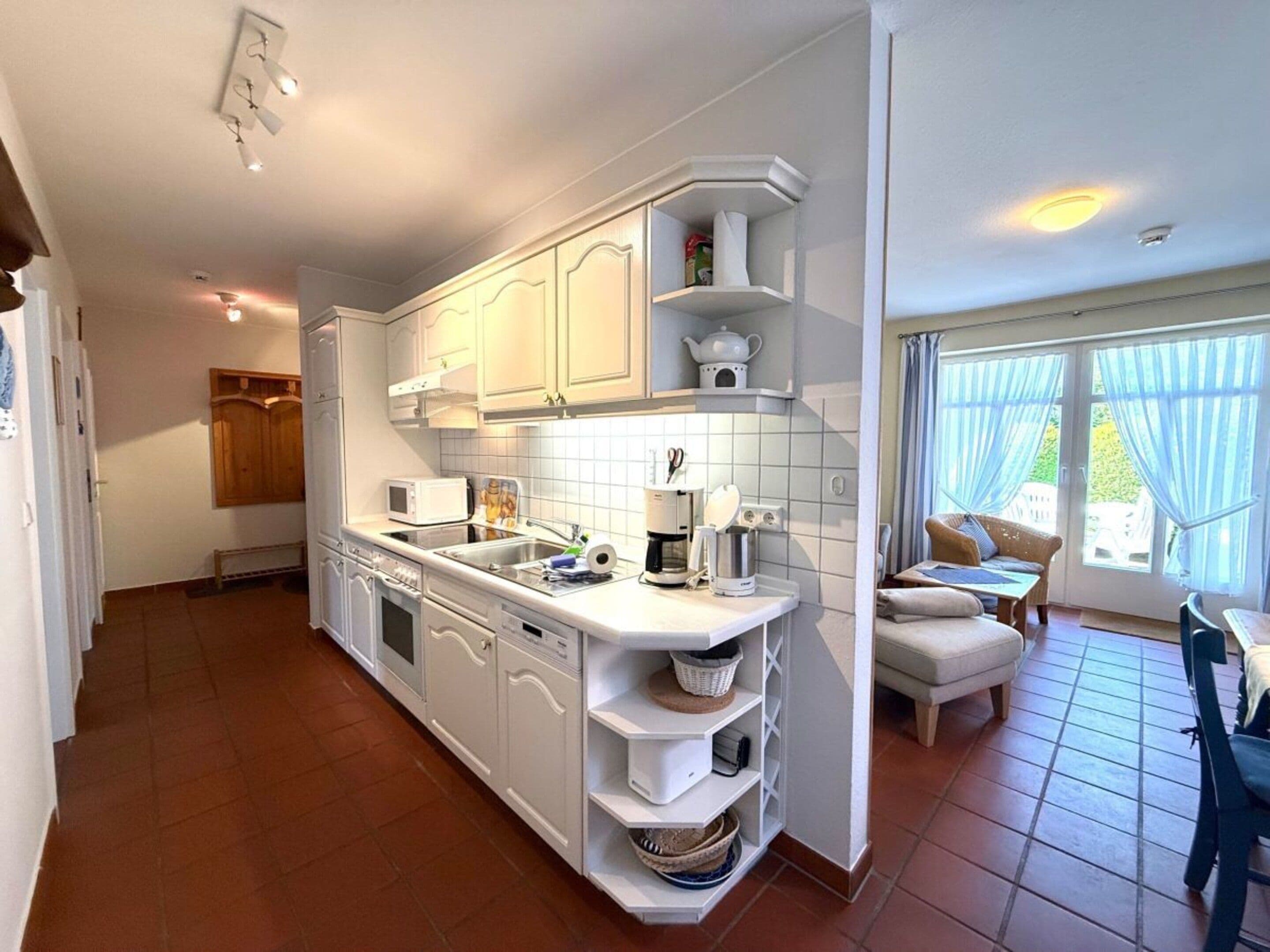 A kitchen with white cabinetry, a built-in oven, and a dining area with a table and chairs.