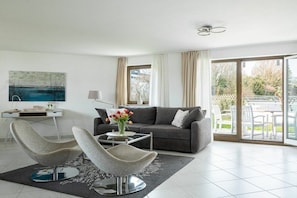 A modern living room with a sofa, two armchairs, a coffee table, and a painting on the wall. - Holiday apartment with 1 bedroom (Überlingen)