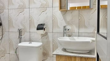 A bathroom with a toilet, a sink, and a mirror.