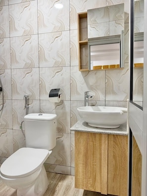 Een badkamer met toilet, wastafel en spiegel.
